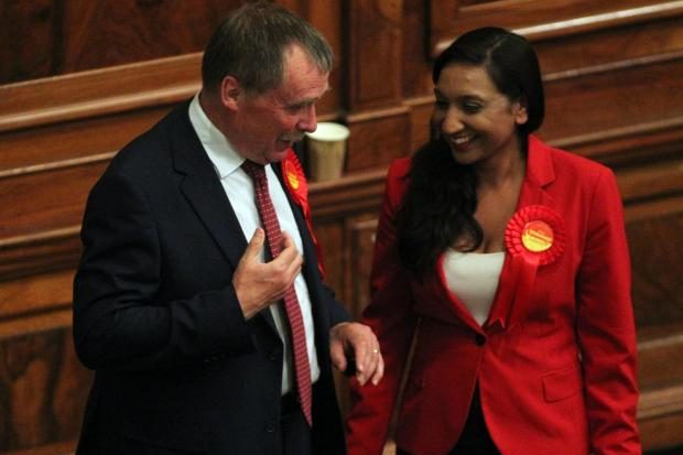 Alan Whitehead and Satvir Kaur wearing Labour red rosettes chatting at an election count