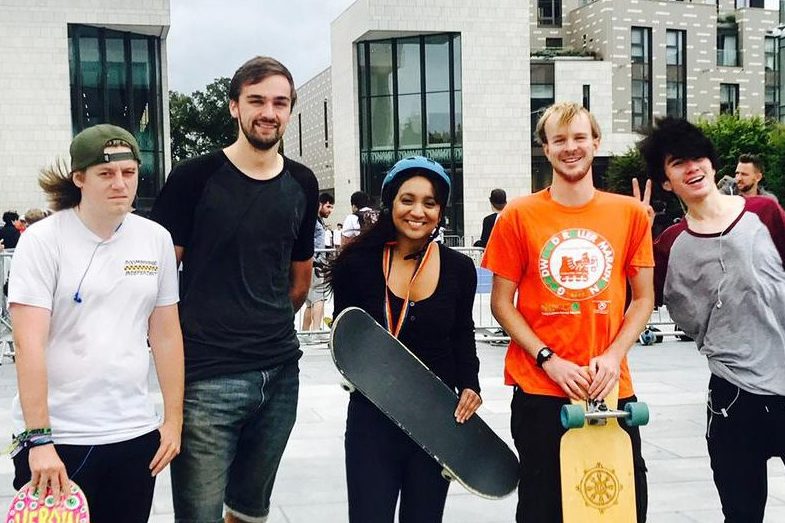 Satvir Kaur wearing a helmet and holding a skateboard, photographed with skateboarders in Guildhall Square 